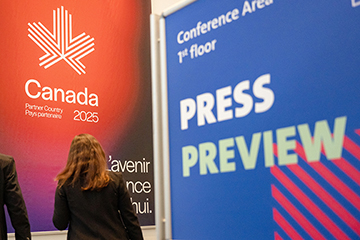 © Deutsche Messe AG. Close-up of the HANNOVER MESSE Press Preview banner, with an attendee looking at the Canada partner country banner in the background.