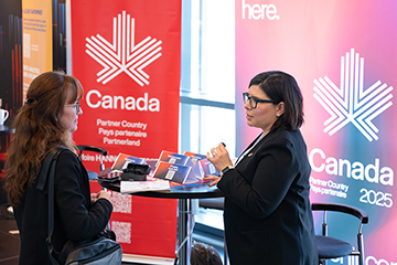 © Deutsche Messe AG. Christina Bilyk, Executive Lead for Canada at HANNOVER MESSE 2025, discussing with an attendee at the Canada booth at the HANNOVER MESSE Press Preview.