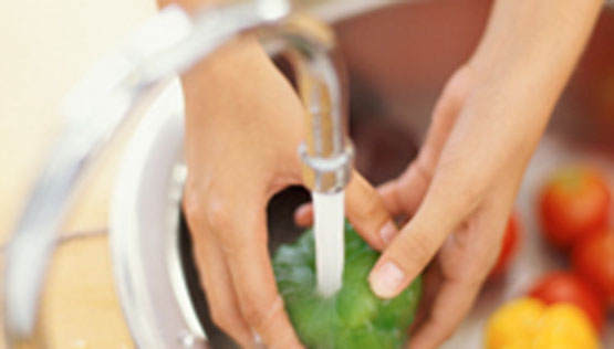 Washing peppers under running water.