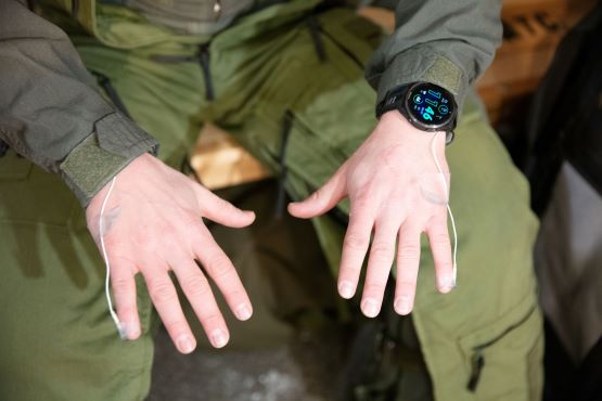 A person shows the temperature monitors on their pinky fingers.